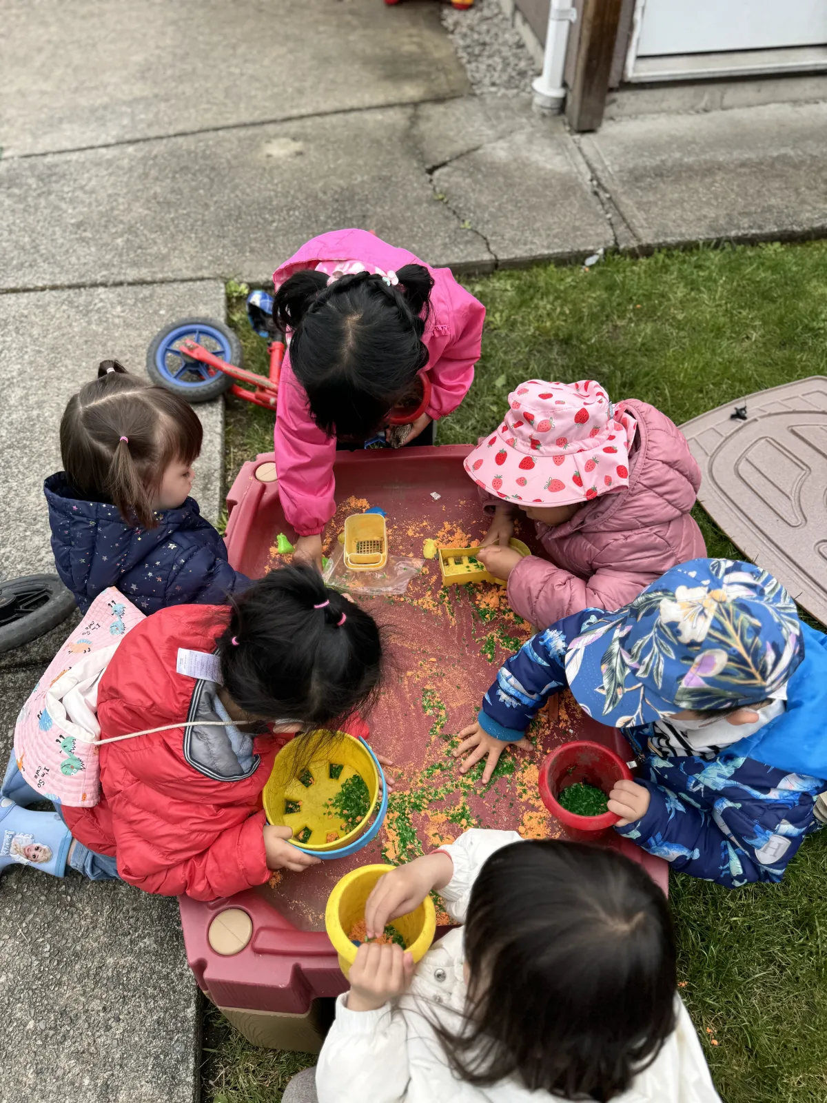 Toddlers playing at an outdoor sensory table in the daycare yard