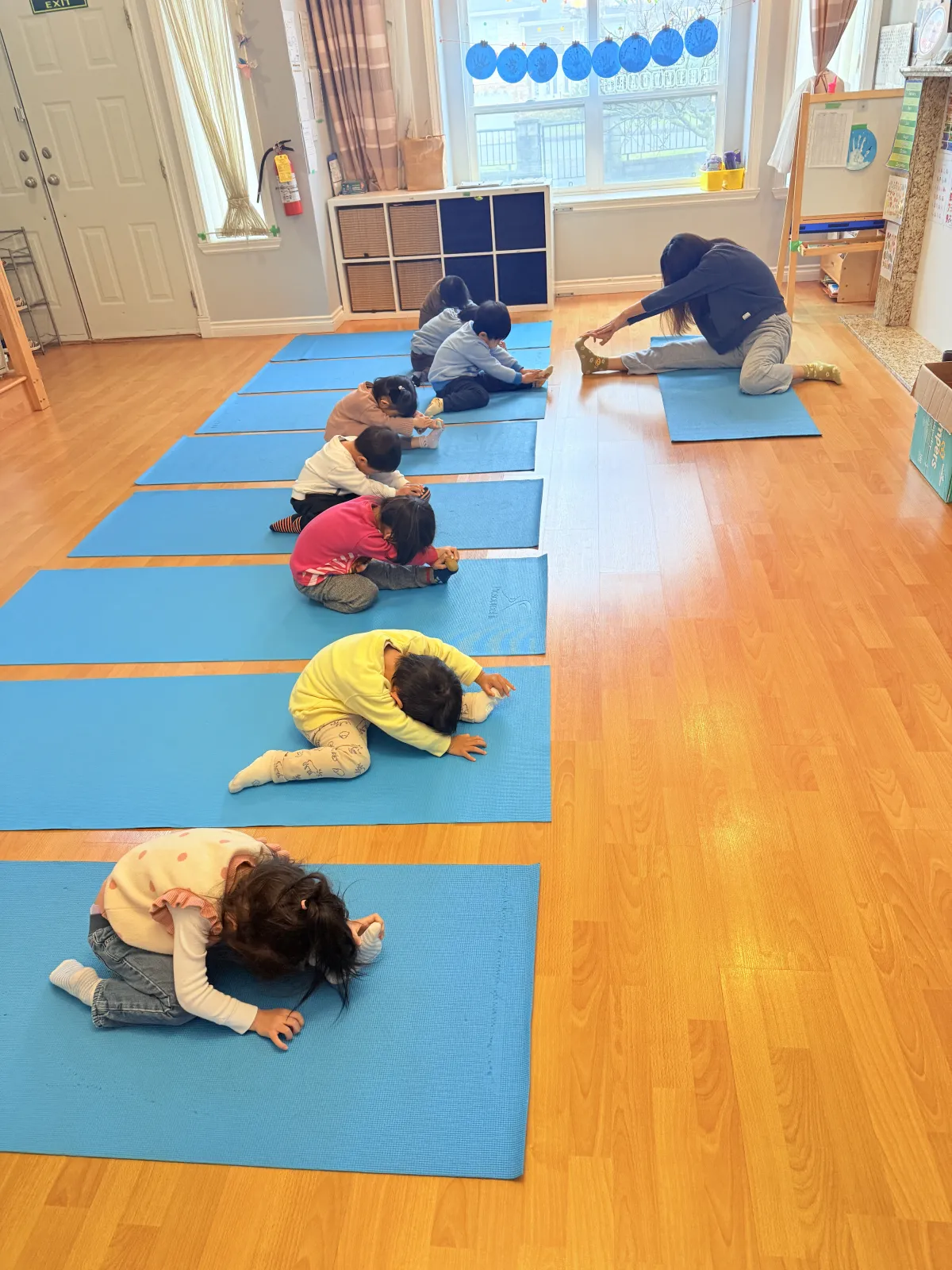 Children stretching on yoga mats with their teacher at A&B Daycare